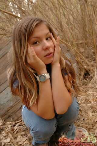 Adorable young girl shows her firm tits amid bushes in cute panties