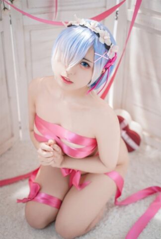 Beautiful Asian model with big tits poses while wrapped in pink satin ribbon